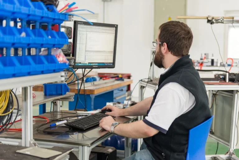 control engineer working on plc programming at workstation in automation lab