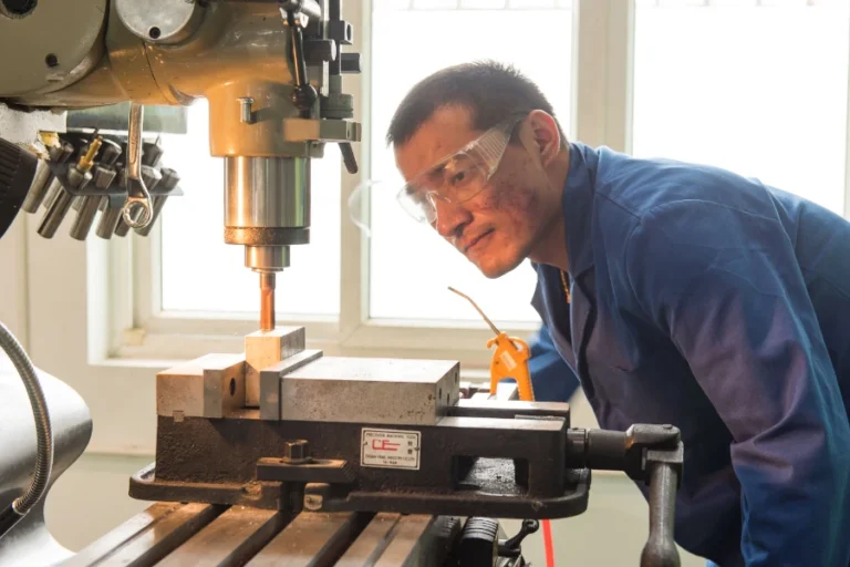 industrial machinist monitoring metal cutting process on vertical milling machine